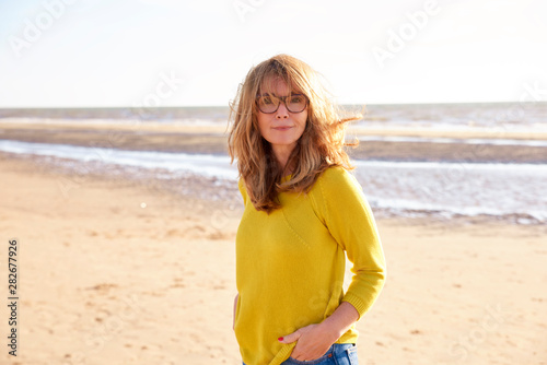 Middle aged woman with frizzy hair walking on the beach