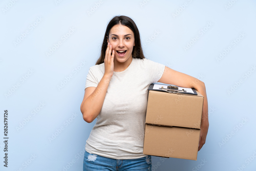 Young delivery woman over blue brick wall with surprise and shocked facial expression Young delivery woman over blue brick wall with surprise and shocked facial expression