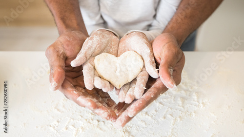 Afro man hands holding child hands with heart shaped pastry photo