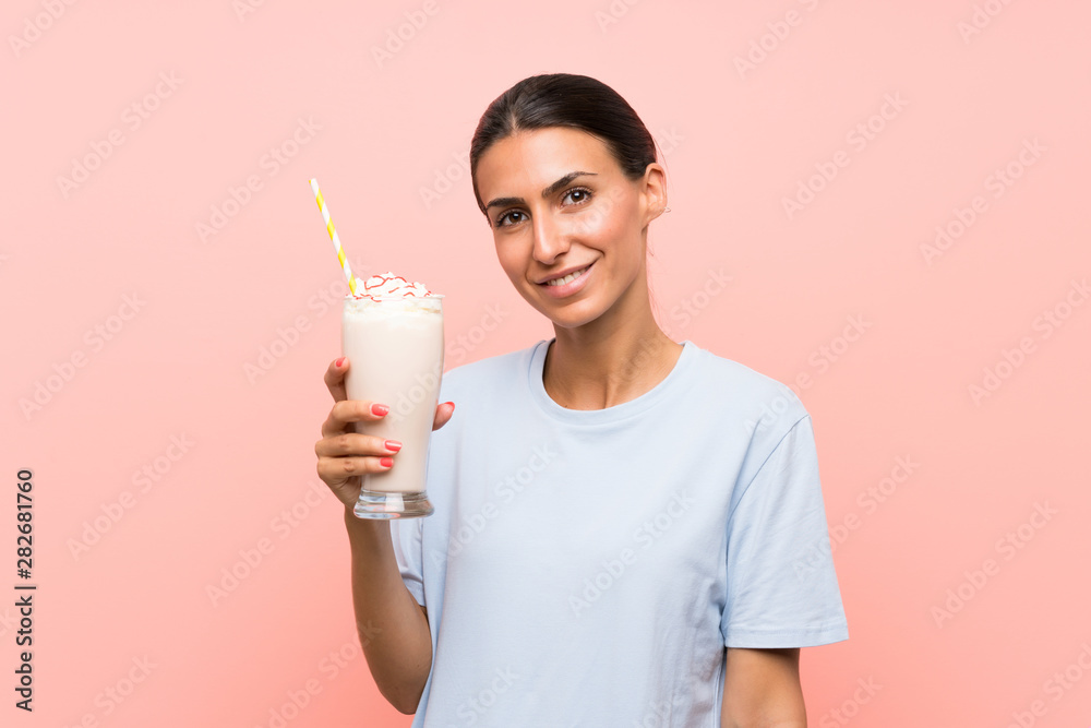 Young woman with strawberry milkshake over isolated pink background smiling a lot Young woman with strawberry milkshake over isolated pink background smiling a lot