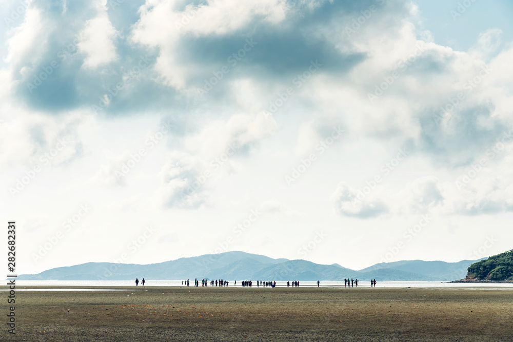 Obraz premium Landscape of low tide with green mountain, cloud sky with people in background at Toong Pronge Bay in Chon Buri, Sattahip District, Thailand.