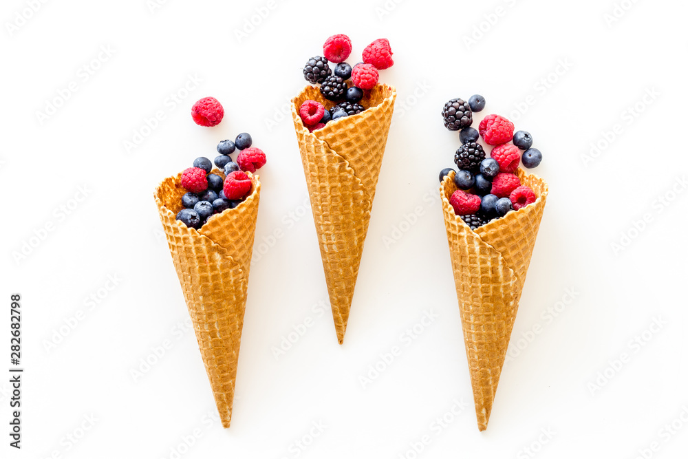 Summer breakfast with fresh berries in waffle cones on white background top view Summer breakfast with fresh berries in waffle cones on white background top view