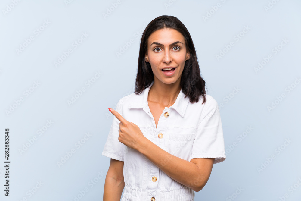 Young woman over isolated blue background pointing finger to the side Young woman over isolated blue background pointing finger to the side