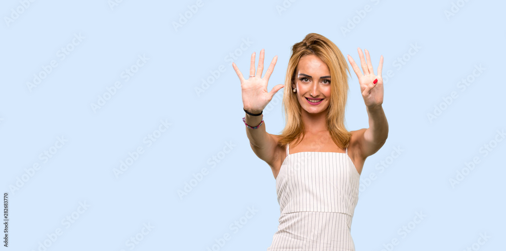 Young blonde woman counting nine with fingers over isolated blue background Young blonde woman counting nine with fingers over isolated blue background