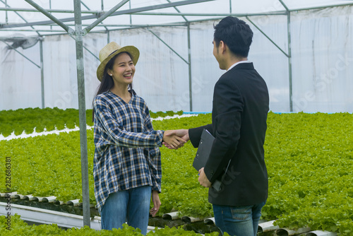 farmer pretty girl shaking hand with businessman in Organic Vegetable Farm hydroponics. Small business success concep