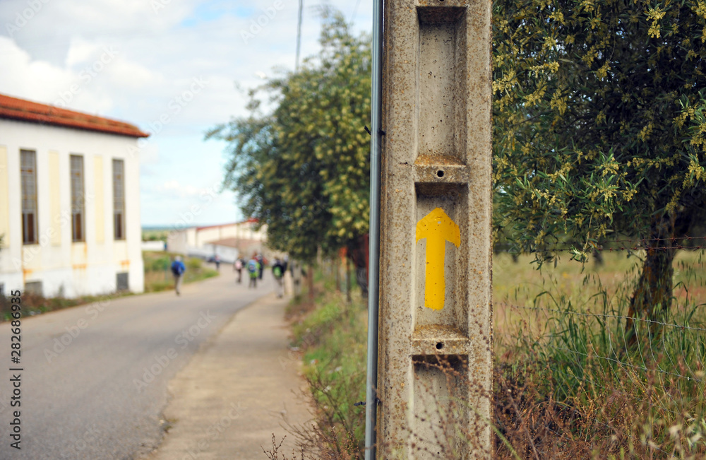 Yellow arrow painted on a cement electric pole, information symbol of the Way of St James (Camino de Santiago) for pilgrims, Extremadura, Spain Yellow arrow painted on a cement electric pole, information symbol of the Way of St James (Camino de Santiago) for pilgrims, Extremadura, Spain