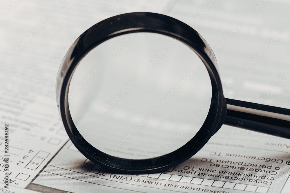 Fototapeta premium Small magnifying glass on paper with text. search, analysis