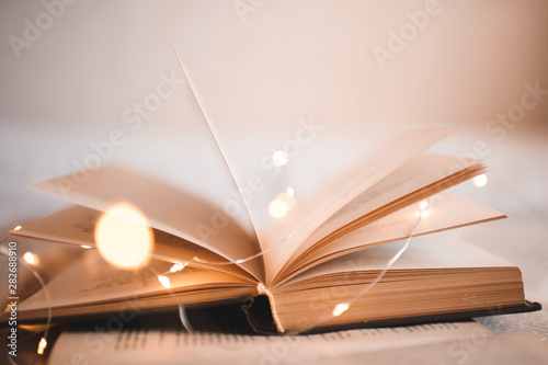 Open book with magic Christmas lights closeup. Selective focus. Good morning. Night time.