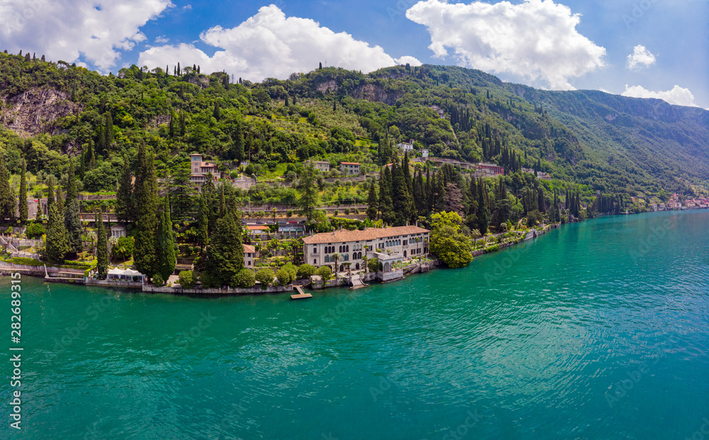 Beautifull aerial panoramic view from the drone to Varenna famous old Italy town on bank of Como lake. High top view to villa Monastero landscape, green hills, mountains and city in sunny summer day