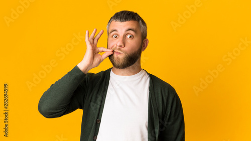 Fotografie Handsome caucasian man zipping his mouth with gesture