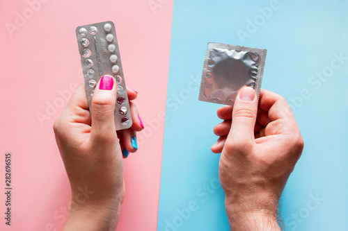 woman holds birth control pills, man holds condom