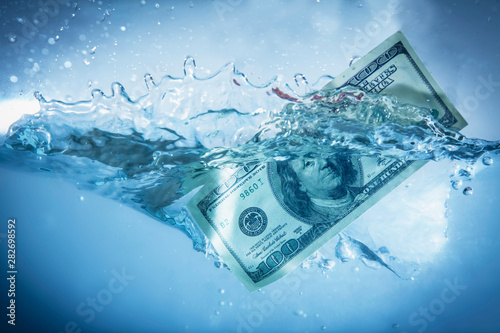 Valokuvatapetti Global financiall crisis concept. US Dollar sinking in water
