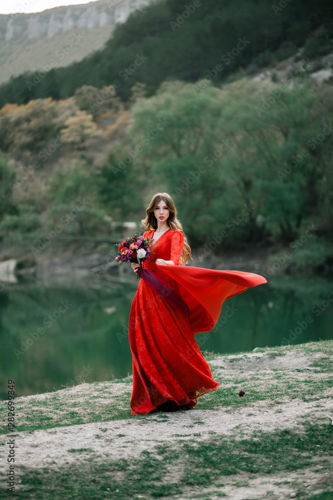Young bride in a red dress with an Assemtric bouquet of pomegranates and roses. Young bride in a red dress with an Assemtric bouquet of pomegranates and roses.