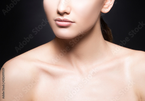 Lips, part of beauty face, shoulders of beautiful young model woman, perfect skin, natural nude makeup. Black background