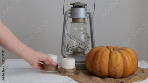 woman puts a candle on a table next to a pumpkin and lanternHalloween autumn concept Video HD photo