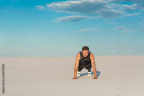 Fitness man doing exercises in sand desert. Sport concept