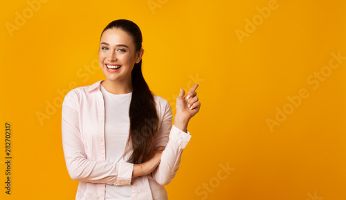 Positive Girl Pointing Finger At Free Space On Yellow Background