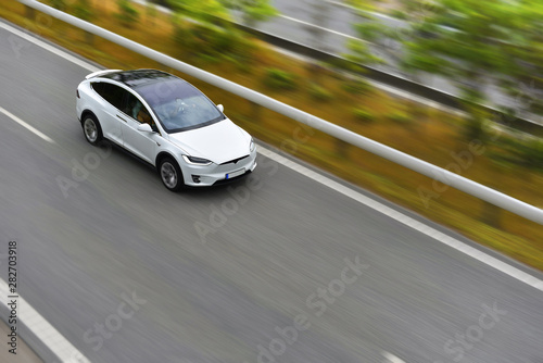 modern electric crossover car is driving by highway on high speed