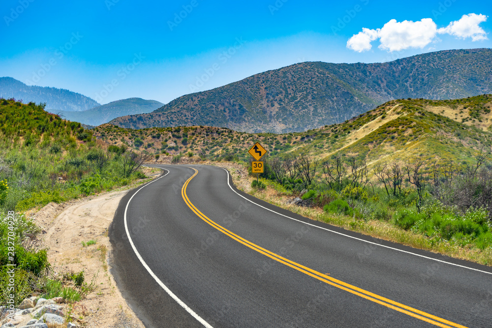 Fototapeta premium Curved mountain road with 30 MPH caution road sign