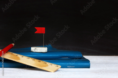 blue notebook and eraser wash with a red flag on the background of the school blackboard. towards the dream