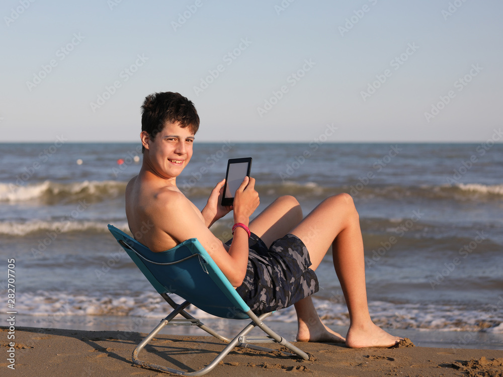boy by the sea reads the ebook on the beach