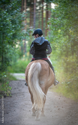 Woman horseback riding in forest and meadow