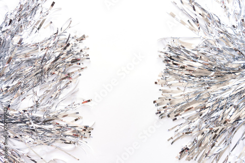 Silver metal foil tinsel strips isolated on white background, christmas or festive decoration garland. Pom-poms cheerleading. New year composition. Flat lay,  copy space. Sparling decorative element.