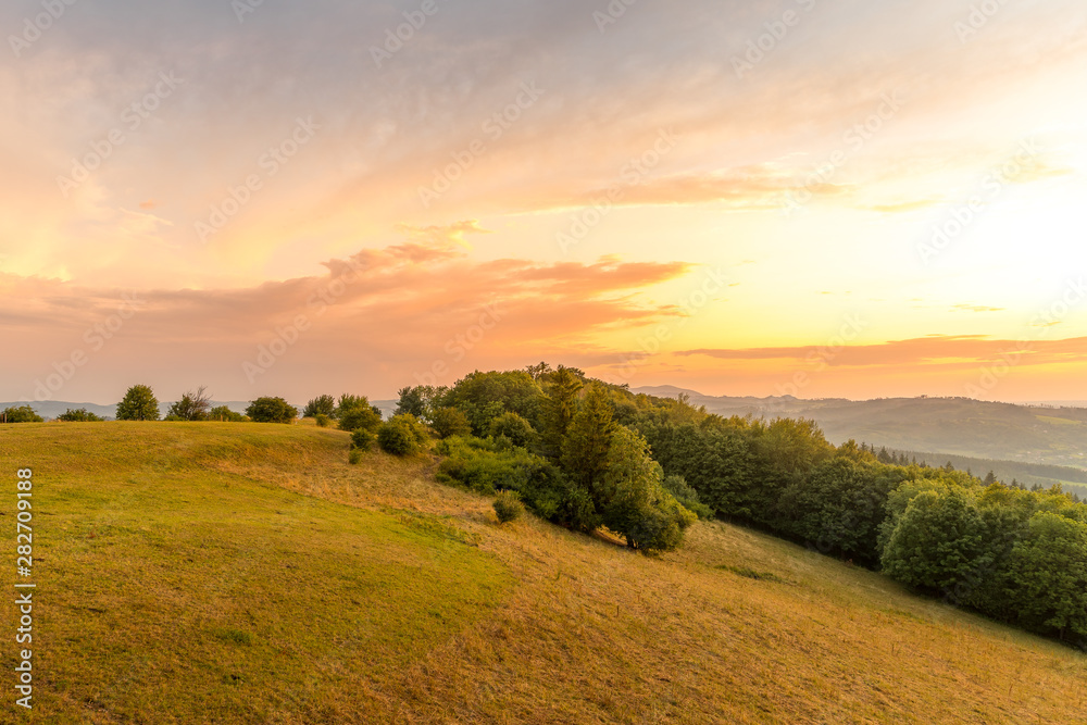 Obraz premium Meadow landscape countryside view with blue sky with many clouds sun light and forest close to city Valasske Mezirici captured during summer late time from hill.