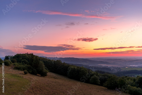 Fototapeta Naklejka Na Ścianę i Meble -  Landscape sunset with fully colored clouds pink orange sky look on meadow close to city Valasske Mezirici captured during summer late time.