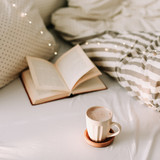 Open book on bedsheets and a cup of coffee. Good morning. Breakfast time. Breakfast in bed. flat lay 