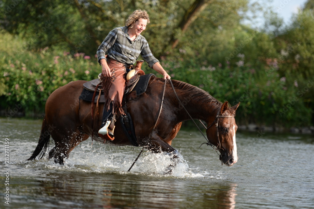 Abkühlung im Fluß. reiterin durchquert mit schönem Pferd einen Fluß