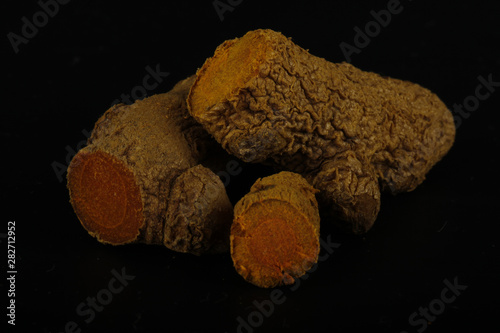 heap of turmeric roots isolated on black background photo