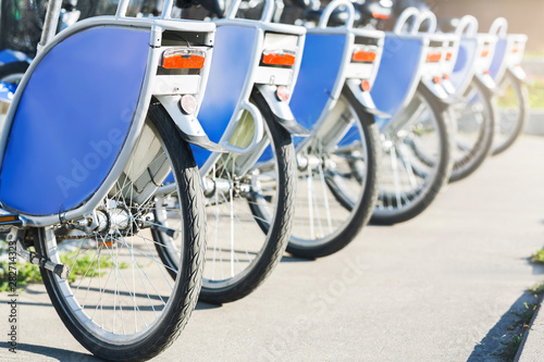 Blue similar bikes stand on parking for rent