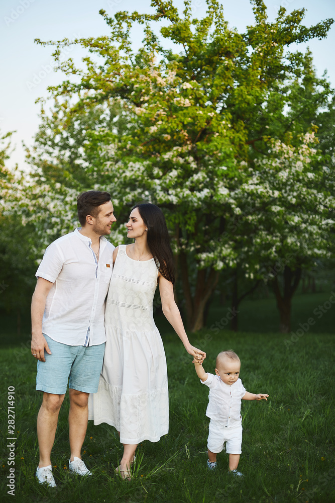 Naklejka premium Front view of happy family in white outfits walking in park