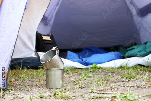 Cuadro en lienzo Metal mugs on ground near camping tent
