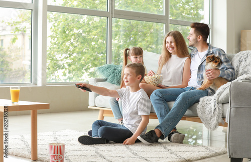Happy family watching TV at...