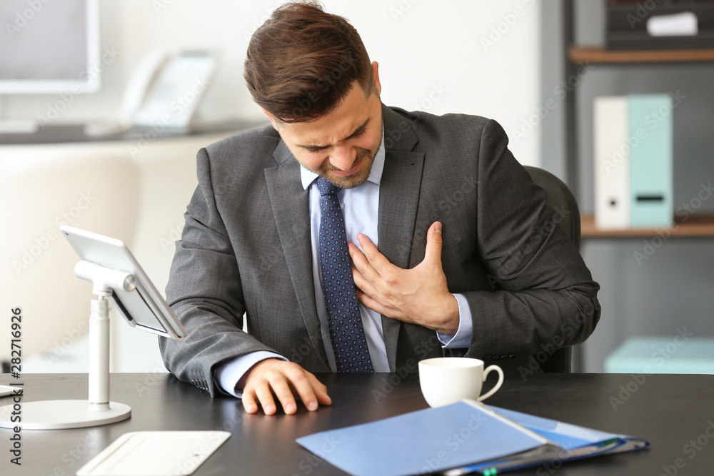 Young businessman having heart attack in office Young businessman having heart attack in office