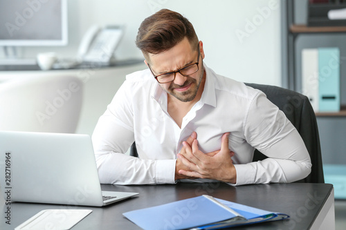 Young businessman having heart attack in office