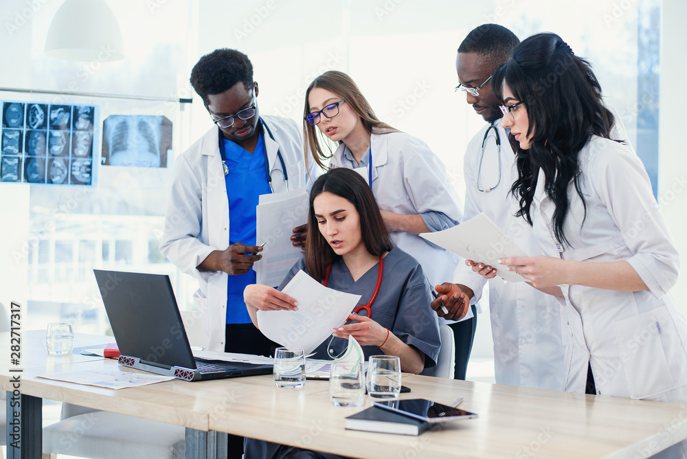 Group of young multi national doctors during working with laptop in the conference room. Group of young multi national doctors during working with laptop in the conference room.