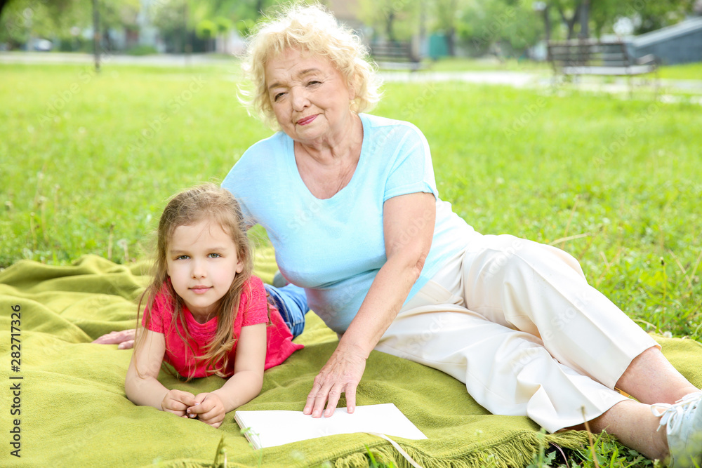 Cute little girl with grandmother resting in park