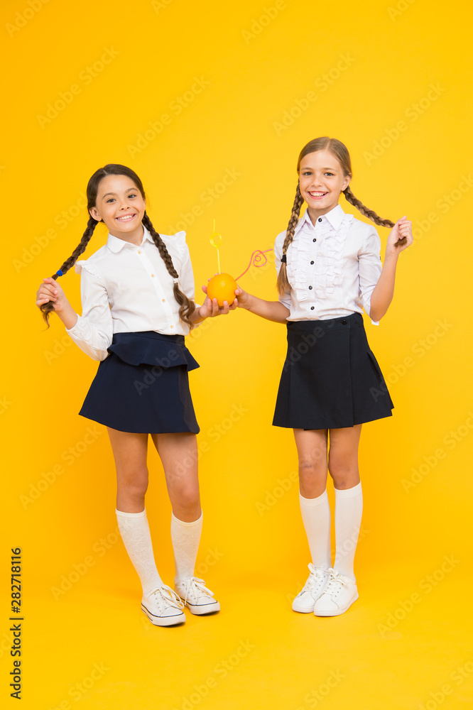 Everyone loves a fresh hairstyle. Small girls with long hairstyle drinking natural juice on yellow background. Little kids with braided hairstyle enjoying orange drink. Hairstyle suitable for school Everyone loves a fresh hairstyle. Small girls with long hairstyle drinking natural juice on yellow background. Little kids with braided hairstyle enjoying orange drink. Hairstyle suitable for school
