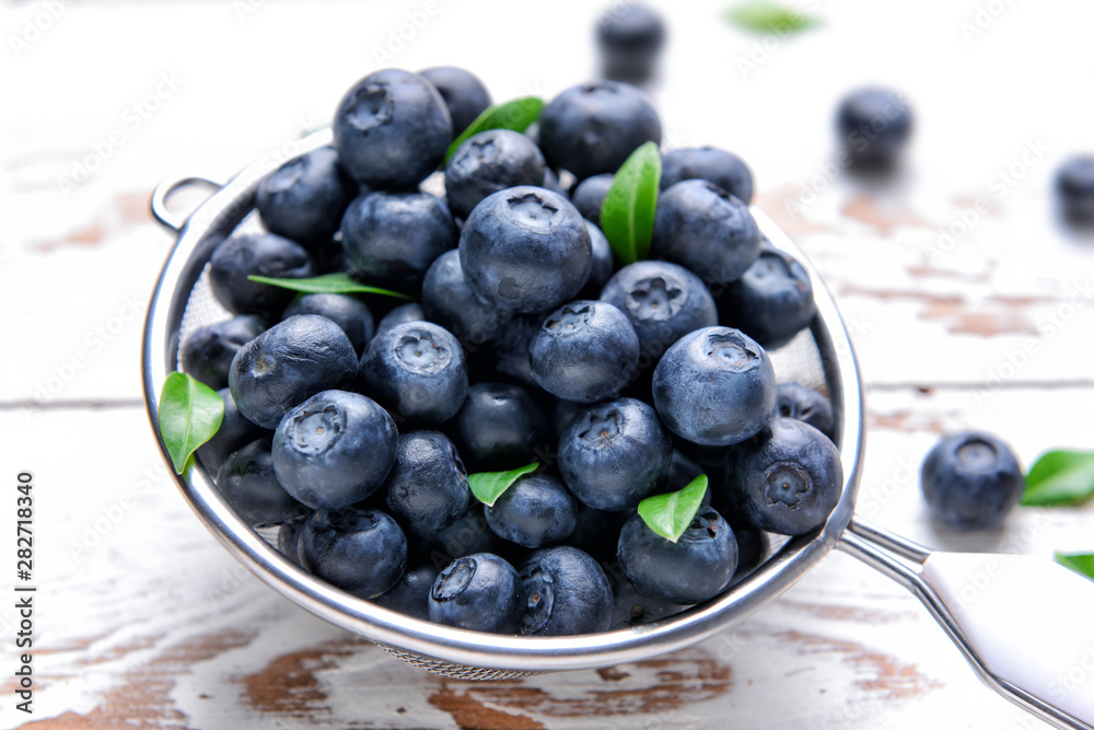 Sieve with ripe blueberry on light wooden background Sieve with ripe blueberry on light wooden background