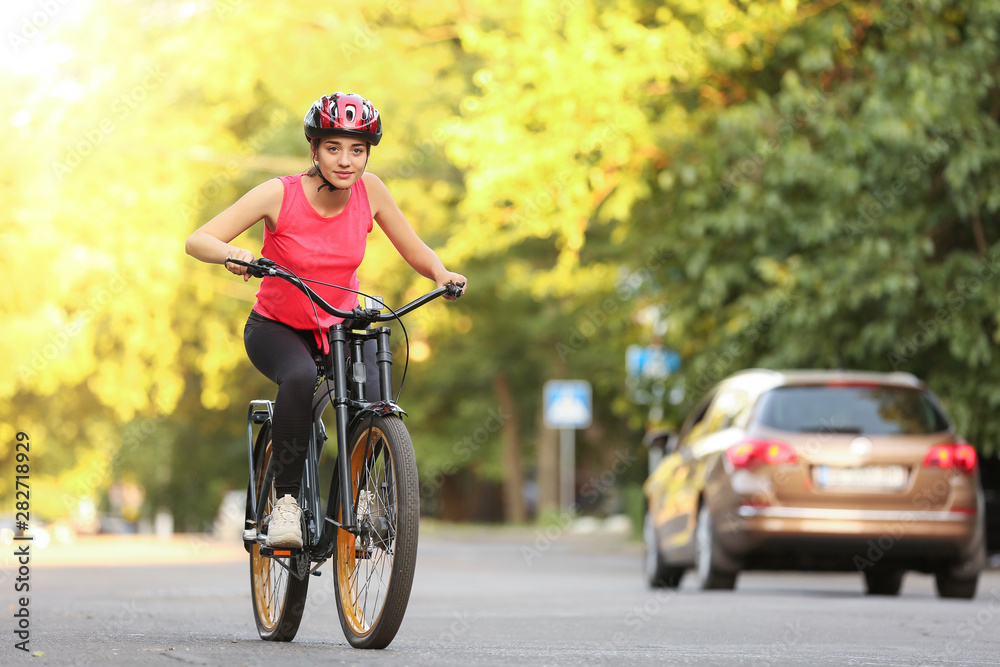 Fototapeta premium Sporty young woman riding bicycle outdoors