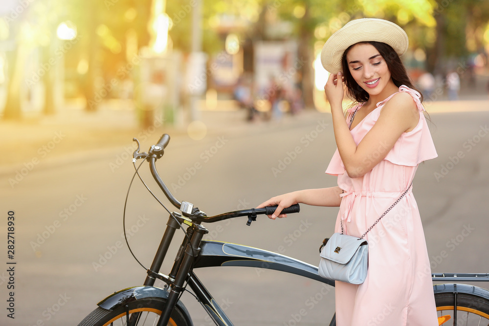 Obraz premium Smiling Young Woman with Bicycle and Hat on Sunny Day