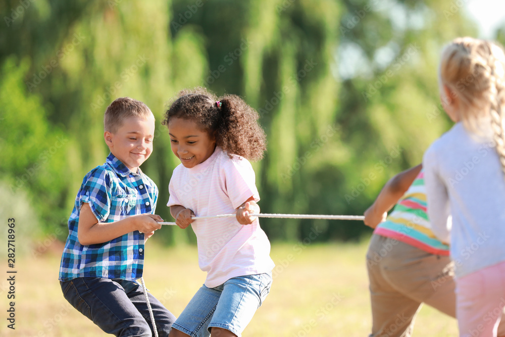Fototapeta premium Group of little children pulling rope in park