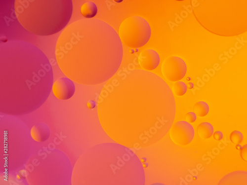 Abstract oil spots in motion on water on blurred yellow background. Photo with small depth of field.