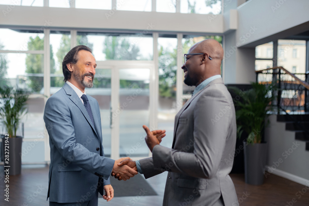 Man smiling while talking to his colleague in the office Man smiling while talking to his colleague in the office