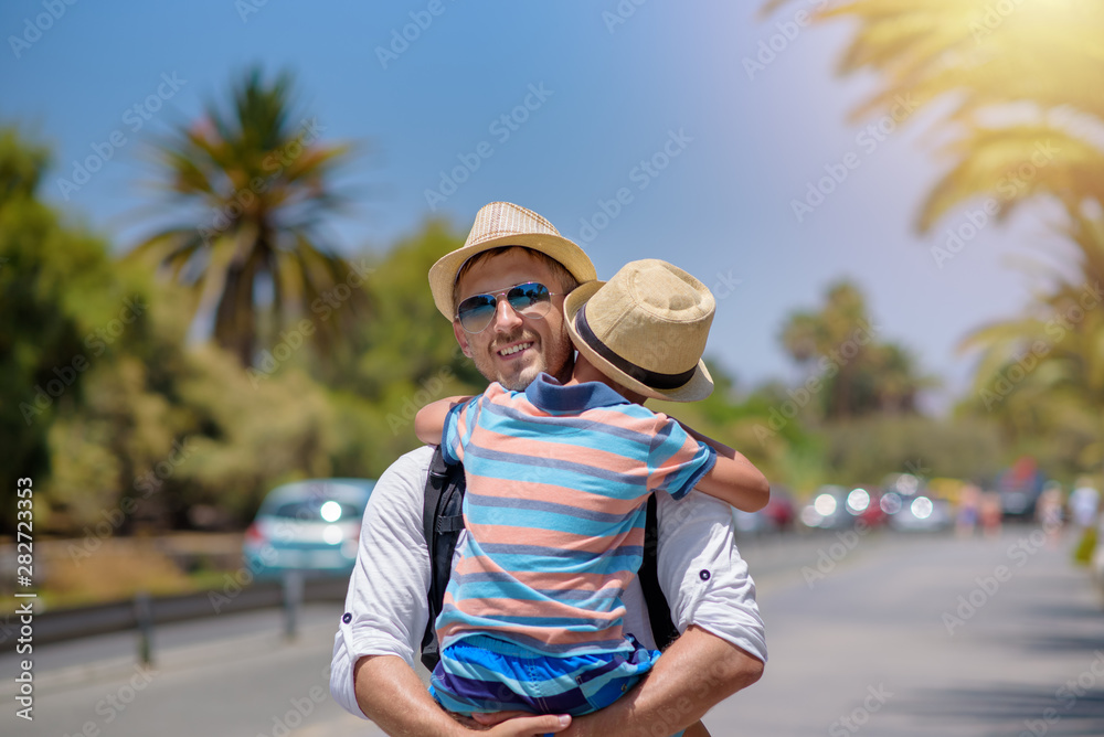Happy father and son hugging while dad holding boy on hands. They spend time together on summer vacations.