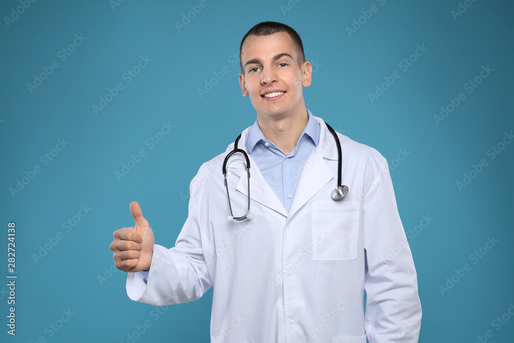 Young man in white coat with stethoscope on color background Young man in white coat with stethoscope on color background