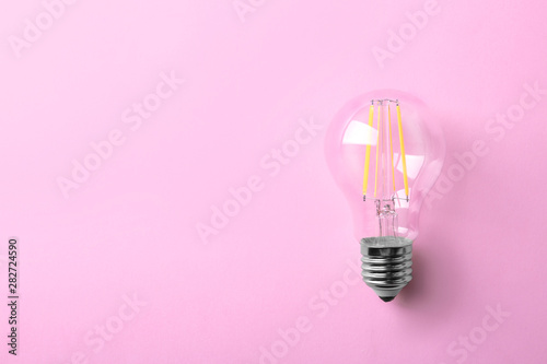 Vintage filament lamp bulb on pink background, top view. Space for text